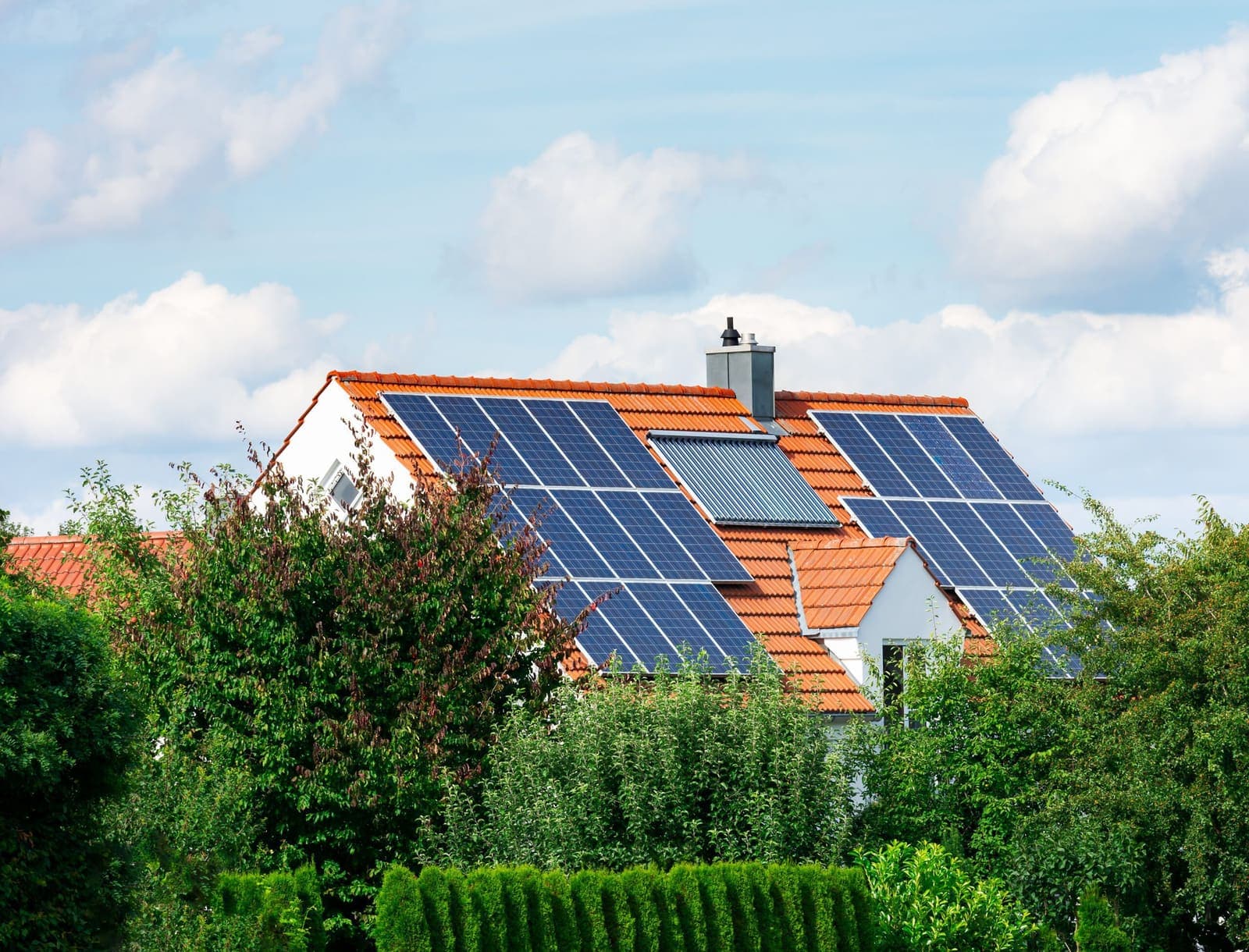 A family home with solar panels on its orange tiled roof
